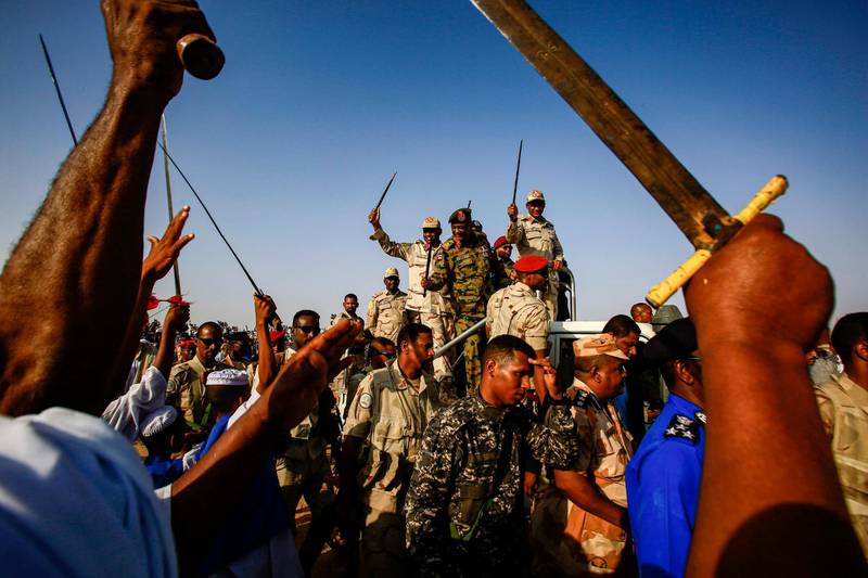 Mohamed Hamdan Dagalo (C-R), also known as Himediti, deputy head of Sudan's ruling Transitional Military Council (TMC) and commander of the Rapid Support Forces (RSF) paramilitaries, waves a baton as he rides in the back of a vehicle surrounded by RSF members and crowds of supporters in the village of Qarri, about 90 kilometres north of Khartoum.  AFP