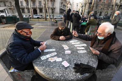 Elderly people wearing face masks play cards in a small park in Milan, northern Italy.  EPA