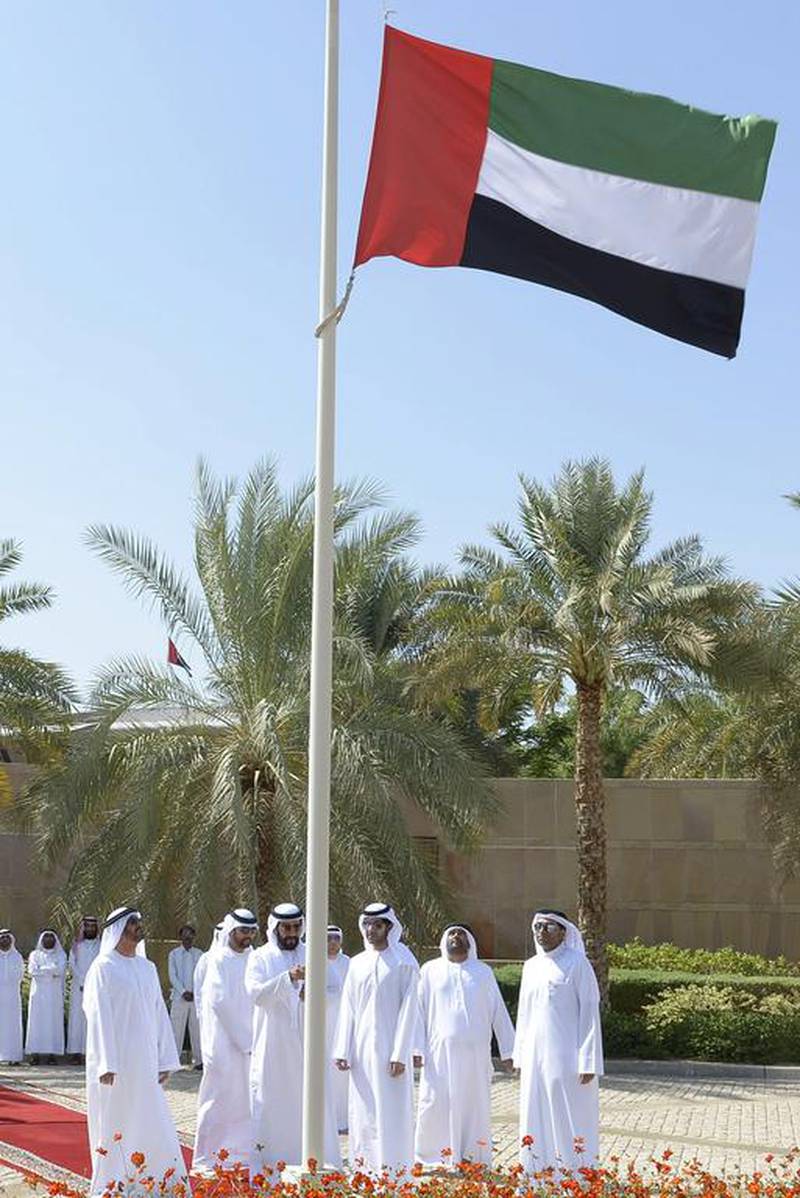 Sheikh Tahnoun bin Mohammed hoists the national flag in his diwan. WAM