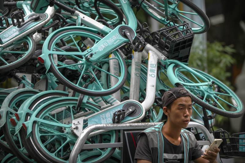 A worker drives a cart loaded with bicycles for a bike-sharing app business in Beijing. AP