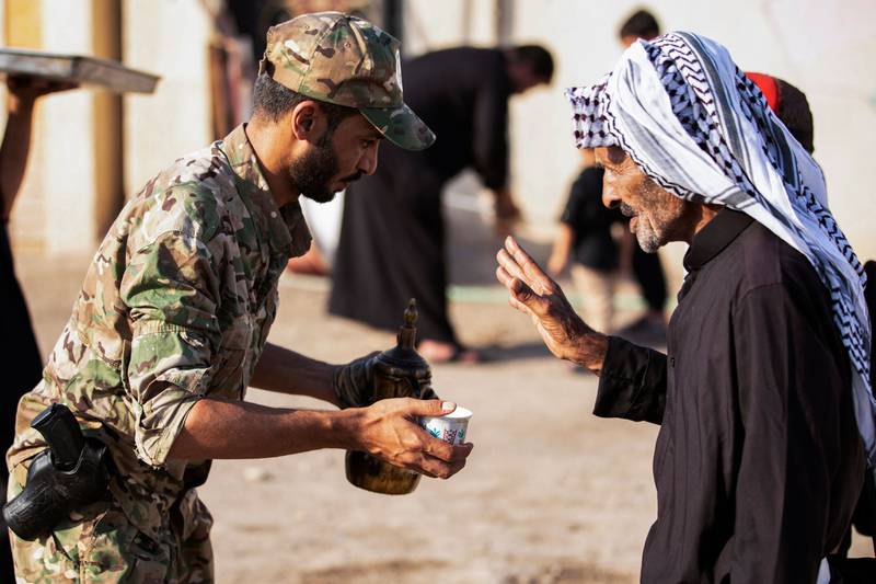 A member of Iraq's Hashed al-Shaabi (Popular Mobilisation) paramilitary forces offers coffee to a pilgrim. AFP