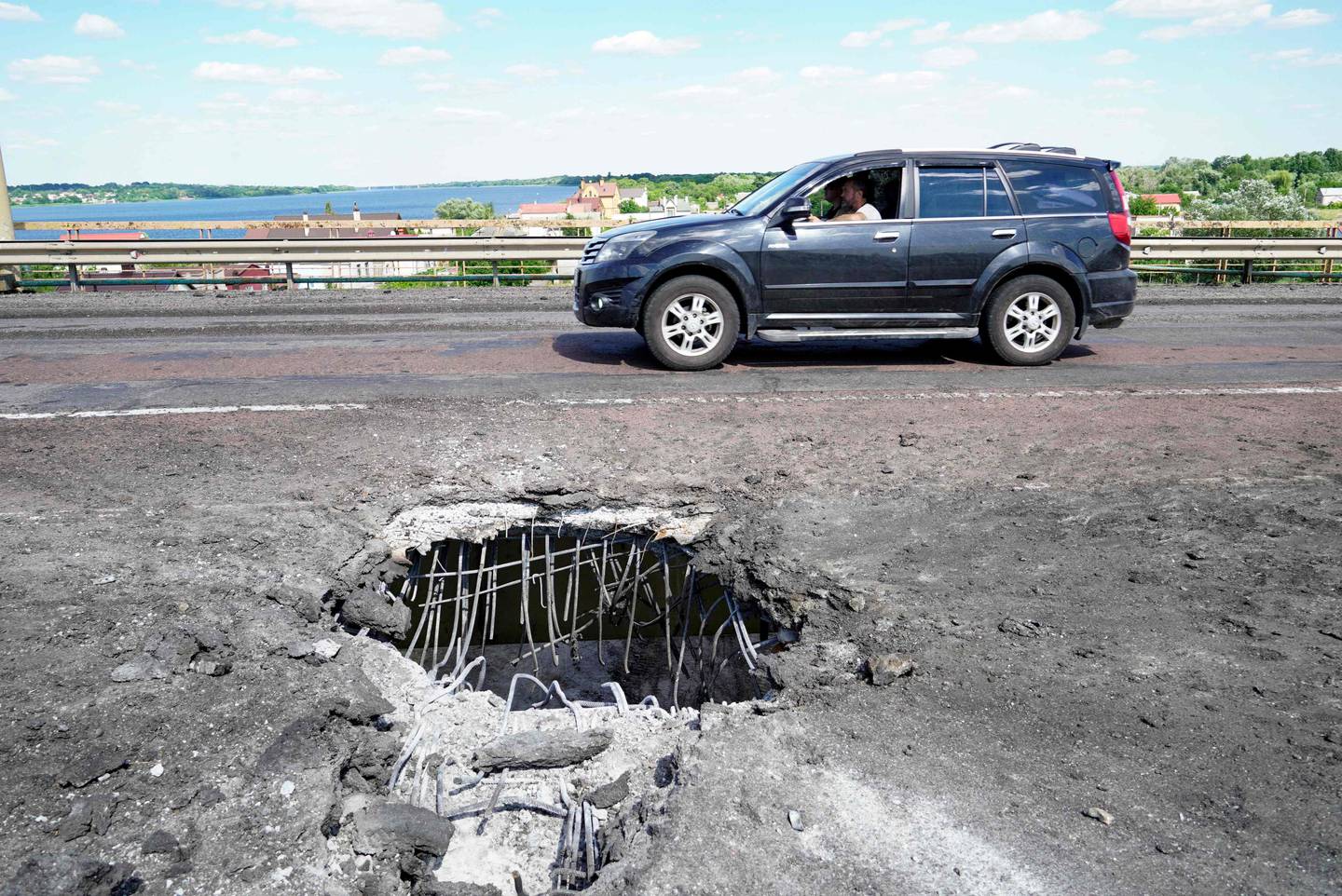 A car moving past a crater on Kherson's Antonovsky bridge across the Dnipro river caused by a Ukrainian rocket strike. AFP
