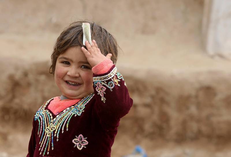 An Afghan refugee girl holds up a small banknote in the Kabobayan refugee camp. AP Photo