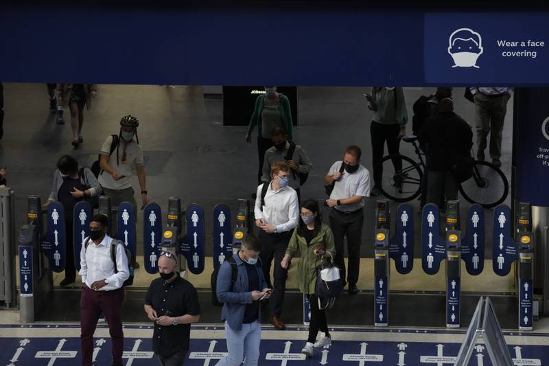 People head through ticket barriers after disembarking a train at Waterloo train station in London.