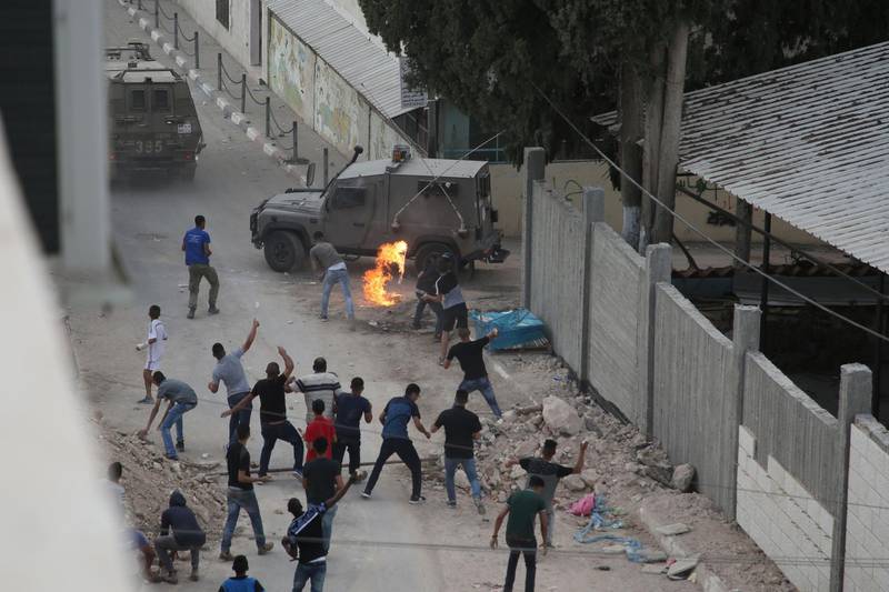 Protesters throw stones and molotov cocktails at Israeli forces in the village of Shuwaykah where the man who shot dead two Israelis earlier used to live, in the occupied west bank, on October 7, 2018. A Palestinian shot dead two Israelis and wounded another at a West Bank settlement's industrial zone on October 7 as security forces hunted the suspected assailant who also worked at the site, the Israeli army said. / AFP / JAAFAR ASHTIYEH
