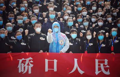 TOPSHOT - Members of a medical assistance team from Jiangsu province chant slogans at a ceremony marking their departure after helping with the COVID-19 coronavirus recovery effort, in Wuhan, in China's central Hubei province on March 19, 2020. Medical teams from across China began leaving Wuhan this week after the number of new coronavirus infections dropped. China on March 19 reported no new domestic cases of the coronavirus for the first time since it started recording them in January, but recorded a spike in infections from abroad. - China OUT
 / AFP / STR
