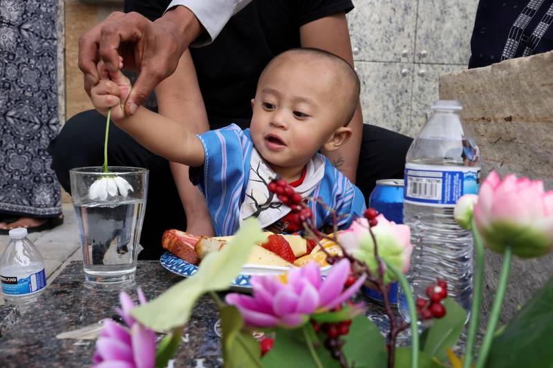Felix San Soe receives help from his grandfather to make a blessing at the grave of his grandmother, Tin Aye, who died a year ago from Covid-19, in Aurora, Colorado, US. Reuters