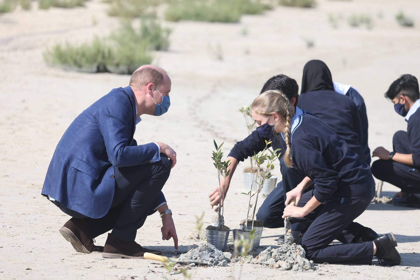Britain's Prince William, Duke of Cambridge, plants trees alongside two school children as he tours Abu Dhabi's wetlands at the Jubail Mangrove Park during an official visit to the UAE on February 10, 2022. PA Wire