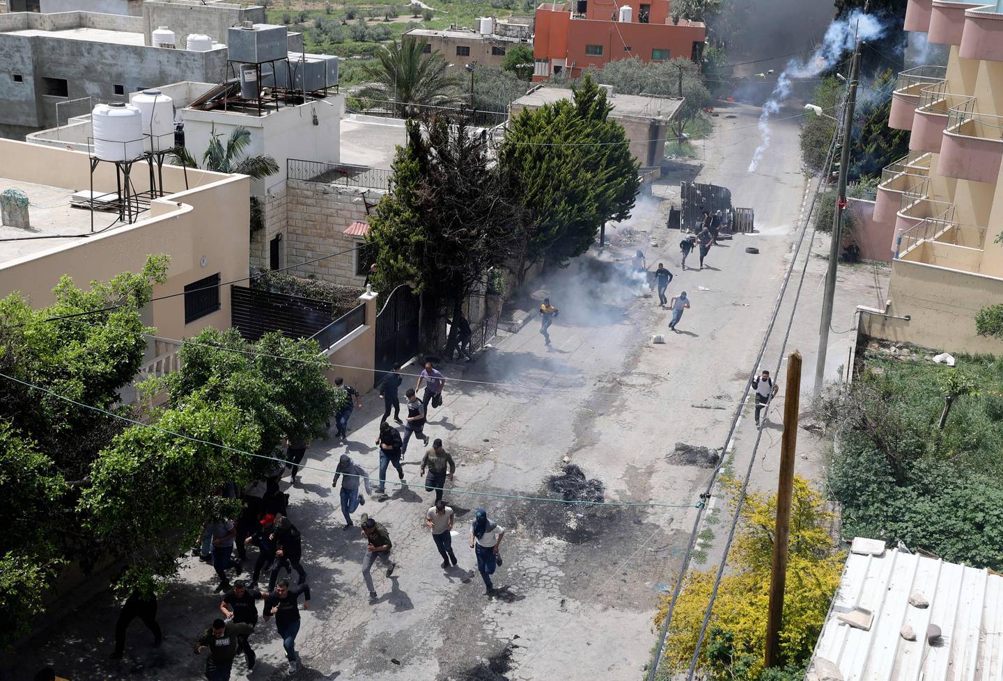 Palestinian protesters run for cover as Israeli forces fire tear gas during clashes in the West Bank . AFP