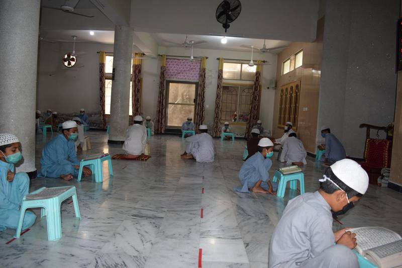 Students observing social distancing rules as they study Quran at their madrasa in Pakistan