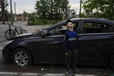 A child looks up at a building destroyed during attacks in Irpin in May 2022