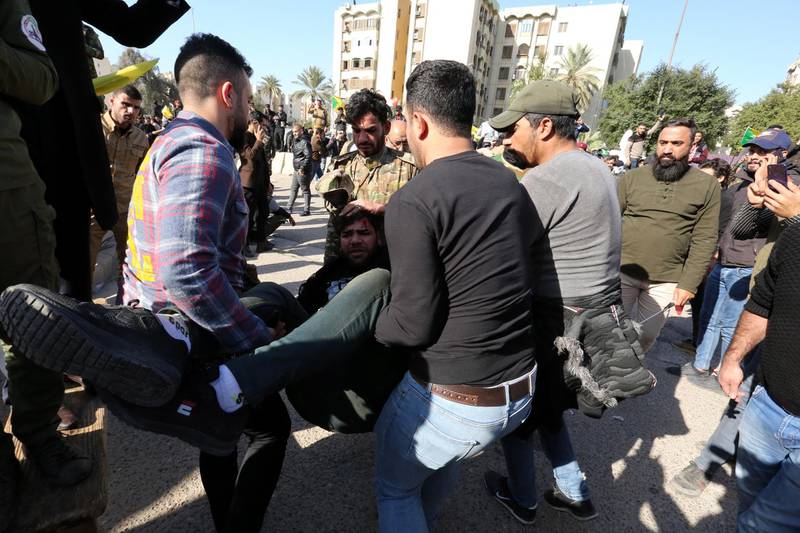 Members of Iraqi Popular Mobilisation Forces and their supporters help their comrade who was wounded during their attempt to attack the US embassy in Baghdad. EPA