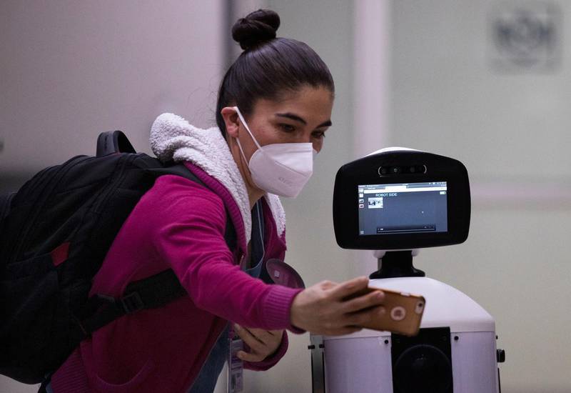 A healthcare worker poses for a photo with Laluchy Robotina, a robot designed to aid in the mental health of patients infected with the new coronavirus, in the COVID-19 ward at 20 de November National Medical Center in Mexico City, Friday, Sept. 25, 2020. The 1.4-meter-tall robot that moves around on wheels visiting COVID-19 patients, is equipped with a camera and display screen which allows the patients to visit with relatives and to also communicate with healthcare workers, helping to reduce the risk of infection. (AP Photo/Marco Ugarte)