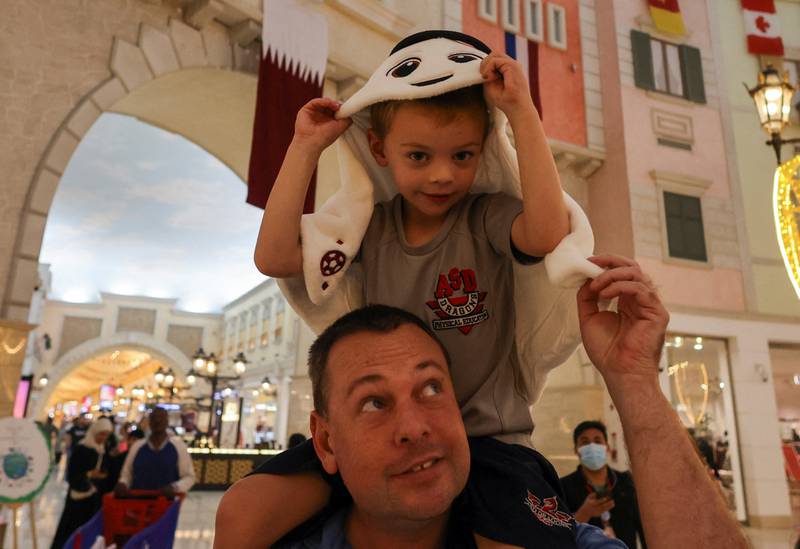 A tourist carries a child wearing the shape of "La'eeb", the Official Mascot for the FIFA World Cup Qatar 2022, at Villaggio Mall in Doha. Reuters
