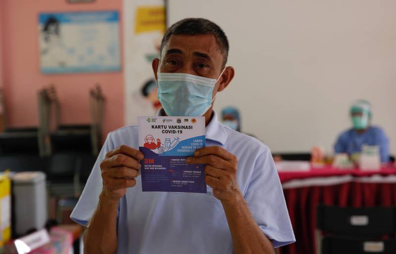A man shows his vaccine card after receiving a dose of the AstraZeneca Covid-19 vaccine during mass vaccination at a district vaccine center in Jakarta, Indonesia. EPA