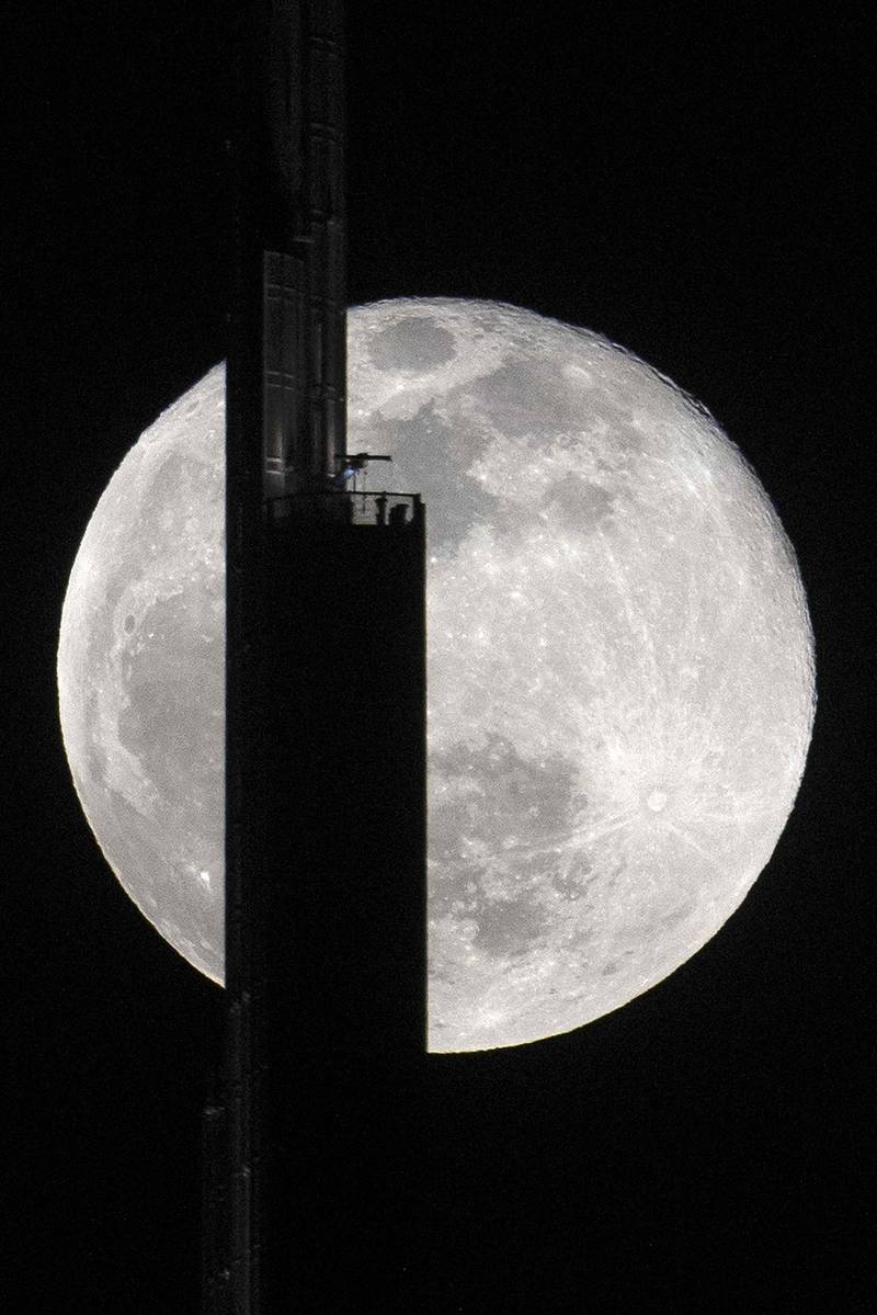 A photo taken on April 27, 2021 shows the April's full moon, known as the Super Pink Moon, behind the Burj Khalifa in Dubai. / AFP / GIUSEPPE CACACE
