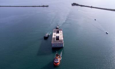 Tug boats bring the three-storey barge to its moorings in Dorset ahead of final inspections. Bloomberg