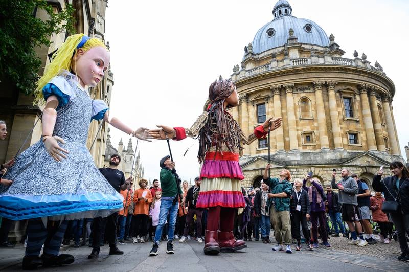 Little Amal and Alice in Wonderland greet children in the city centre of Oxford as part of The Walk, a cross-border project highlighting the plight of unaccompanied child refugees. Getty Images