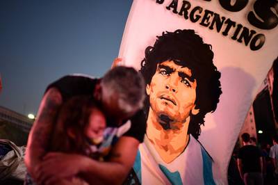 A father and daughter mourn as they gather by the Buenos Aires Obelisk to pay homage to Maradona. AFP