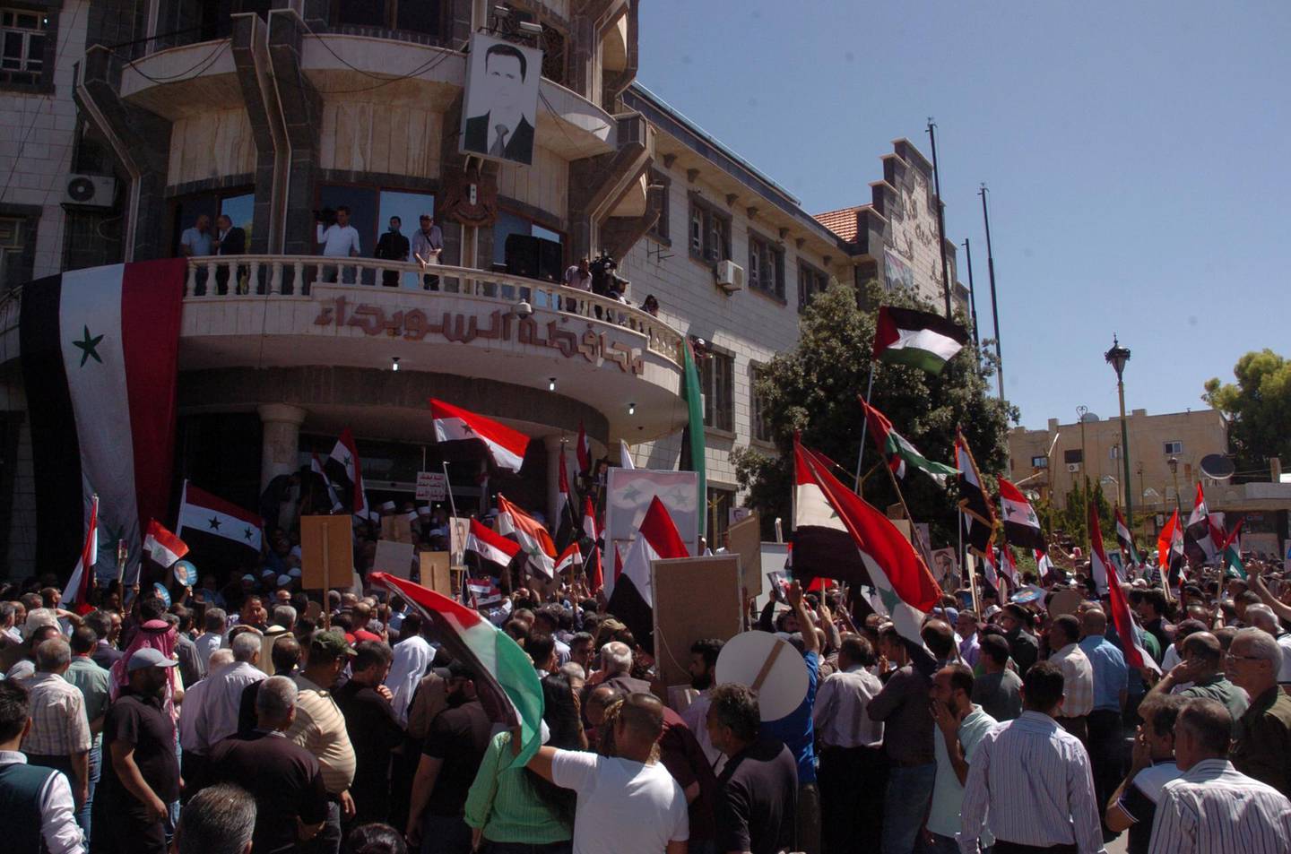 Supporters of Syria's President Bashar al-Assad carry his pictures and flags during a demonstration, in front of the provincial government offices, in the mainly Druze city of Sweida, Syria in this handout released by SANA on June 10, 2020. SANA/Handout via REUTERS ATTENTION EDITORS - THIS IMAGE WAS PROVIDED BY A THIRD PARTY. REUTERS IS UNABLE TO INDEPENDENTLY VERIFY THIS IMAGE