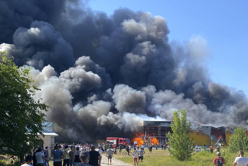 People watch as smoke rises after a Russian missile strike hit a crowded shopping mall, in Kremenchuk. AP