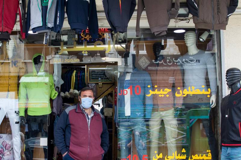 A clothes shop owner wearing a protective faced mask is waiting for customers in Downtown Amman. EPA