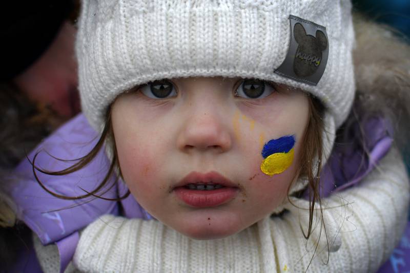 Zlata, 3, with her face painted in the colours of the Ukrainian flag, stands on the Romanian side of the border with Ukraine after fleeing the country. AP