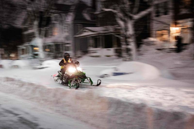 A person rides a snowmobile along a residential street in Buffalo. AFP