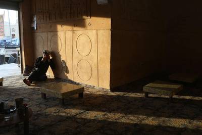 A restaurant worker sits among empty tables as he waits for customers in Siwa.