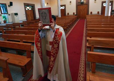 Priest Martin Beni takes part in a Holy Friday ceremony, the Deposition of Christ, held during a curfew to help fight the spread of the coronavirus in almost empty Our Lady of Salvation Church in Baghdad, Iraq. AP