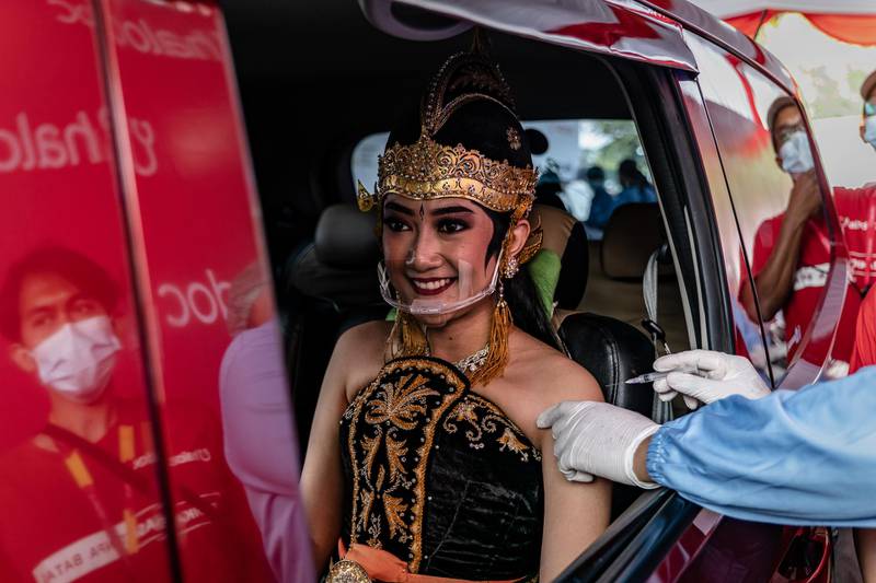 A woman wearing javanese traditonal costume in a vehicle receives a dose of the Sinovac Biotech Ltd. Covid-19 vaccinein during a mass drive-thru vaccination program at Prambanan temple complex in Yogyakarta, Indonesia. Getty Images