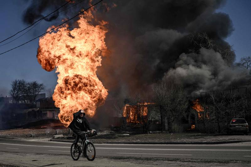 A cyclist rides past flames and smoke rising from a blaze caused by artillery fire in Kharkiv. Russian strikes aimed at a medical centre in the city killed at least four civilians, Ukrainian officials said. AFP
