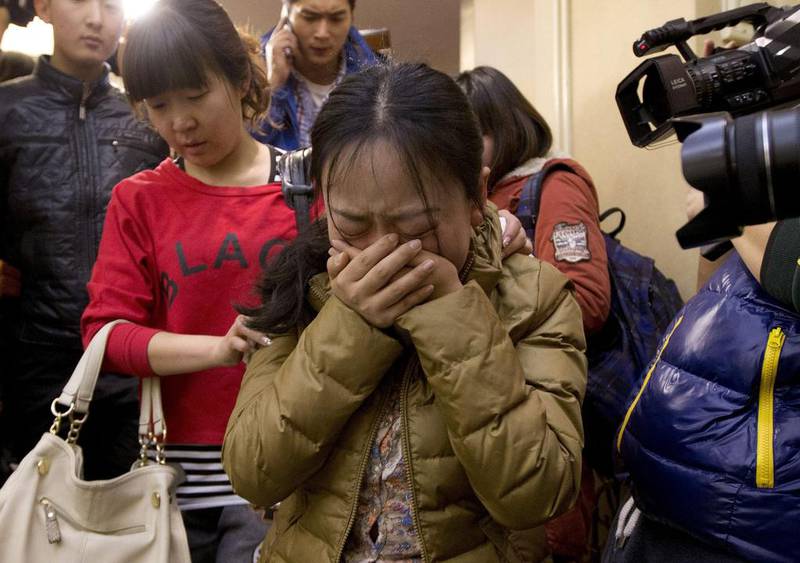 A Chinese relative is escorted by a woman while leaving a hotel room for relatives or friends of passengers. Andy Wong / AP Photo