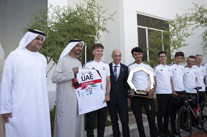 Sheikh Mohamed bin Zayed, Crown Prince of Abu Dhabi and Deputy Supreme Commander of the Armed Forces, second left, stands for a photograph with Matar Suhail Al Yabhouni, Chairman of ADCC, left, and cyclists from the UAE Tour 2022.