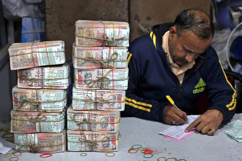 An employee fills a form after counting stacks of old 1,000 Indian rupees inside a bank in Jammu. Mukesh Gupta / Reuters