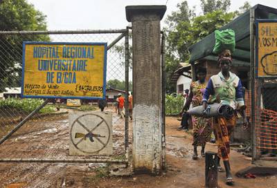 A woman exits the hospital in Bossangoa next to a sign that prohibits people from bringing in weapons