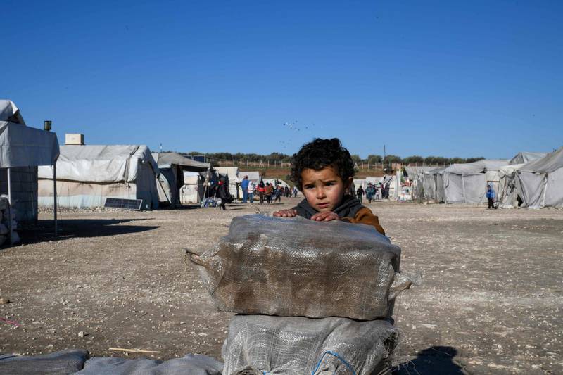 A displaced Syrian boy stands next to bags of aid at a camp for the internally displaced near Dayr Ballut, near the Turkish border in the rebel-held part of Aleppo province.   AFP
