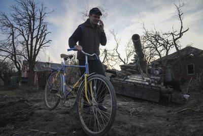 A man wheels his bicycle past a destroyed tank in Chernihiv. AP