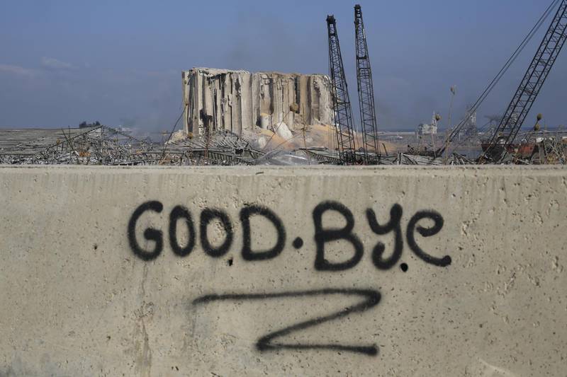 BEIRUT, LEBANON - AUGUST 05: A graffitied wall reading "goodbye" pictured in front of the smoldering buildings in the city's port, destroyed by an explosion a day earlier, on August 5, 2020 in Beirut, Lebanon. As of Wednesday morning, more than 100 people were confirmed dead, with thousands injured, when an explosion rocked the Lebanese capital. Officials said a waterfront warehouse storing explosive materials, reportedly 2,700 tons of ammonium nitrate, was the cause of the blast. (Photo by Marwan Tahtah/Getty Images)