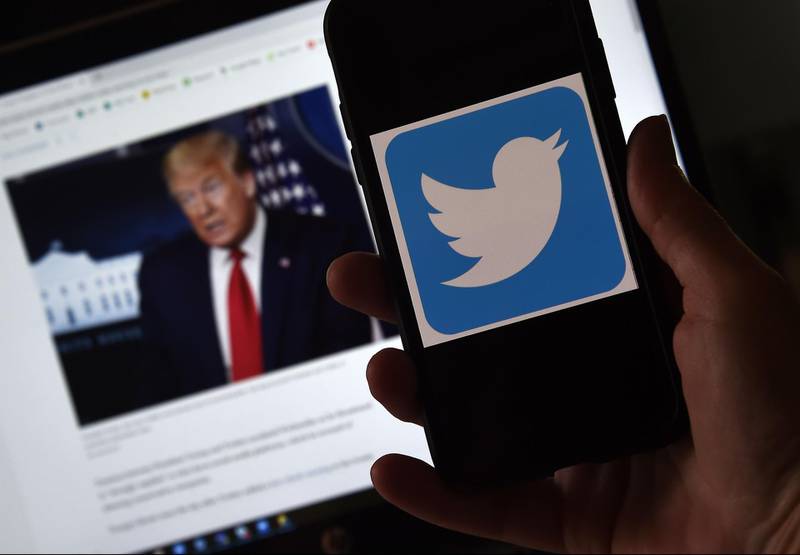 In this photo illustration, a Twitter logo is displayed on a mobile phone with a President Trump's picture shown in the background on May 27, 2020, in Arlington, Virginia.  US President Donald Trump threatened Wednesday to shutter social media platforms after Twitter for the first time acted against his false tweets, prompting the enraged Republican to double down on unsubstantiated claims and conspiracy theories. Twitter tagged two of Trump's tweets in which he claimed that more mail-in voting would lead to what he called a "Rigged Election" this November. / AFP / Olivier DOULIERY
