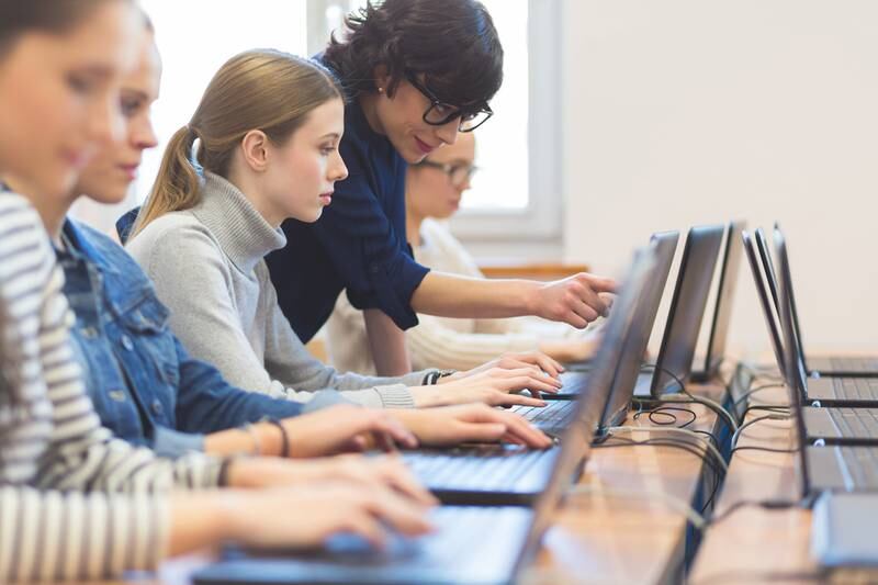 A group of students coding on laptops in a computer lab. The Abu Dhabi Department of Economic Development has added 'computer systems and software designing' to the freelancer licence category.