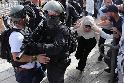 A Palestinian woman runs close to Israeli security force members during violence at the Damascus Gate, just outside Jerusalem's Old City. Reuters