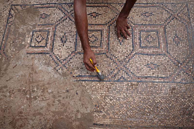 Mr Al Nabahin cleans a section of the mosaic with a brush. AFP