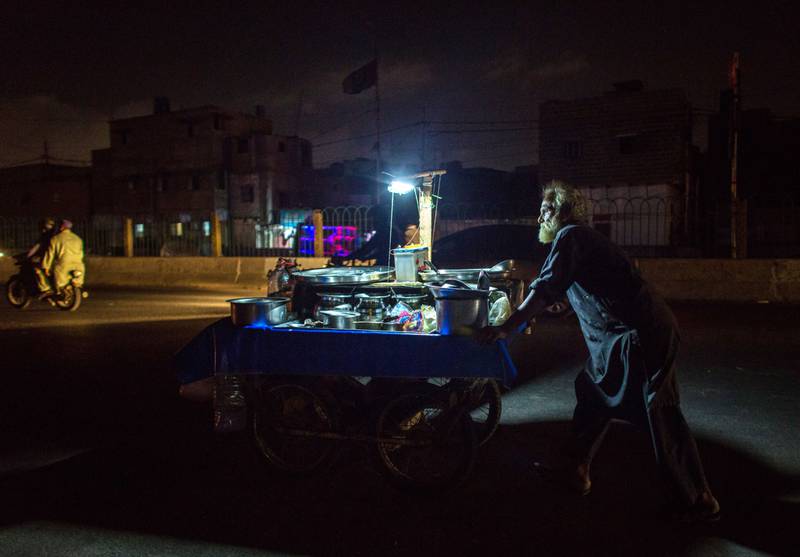 A vendor pushes a cart under an LED light connected to a battery.