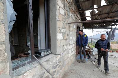 Men are seen next to a house damaged by recent shelling during the military conflict over the breakaway region of Nagorno-Karabakh, in Stepanakert. Reuters
