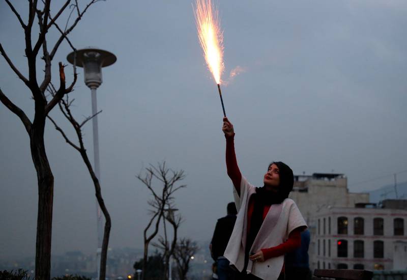 A woman holds a flare aloft during the Charshanbeh Suri fire festival, in Tehran. EPA