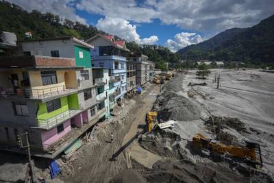 Heavy machinery is used to clear mud and sand near the banks of the Teesta river in Rongpo, Sikkim state, after houses and bridges were washed away. AP