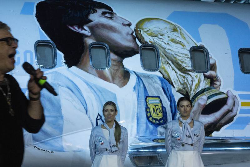 Flight attendants stand by as rock singer Juanse performs during the presentation of an aircraft dedicated to the late  Diego Maradona at a military base in Moron, on the outskirts of Buenos Aires, Argentina. AP