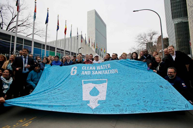 Australian water scarcity activist Mina Guli, centre, holds a banner with supporters after completing her 200th marathon outside UN headquarters, ahead an international water conference in New York this week. Guli ran 200 marathons in the span of a year to draw attention to the water crisis. AFP