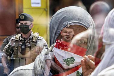 A Lebanese protester wearing a Lebanese flag face mask as members of the Lebanese Armed Forces stand guard during a demonstration against dwindling economic conditions, at Al Nour Square in the centre of Tripoli, May 3, 2020. AFP